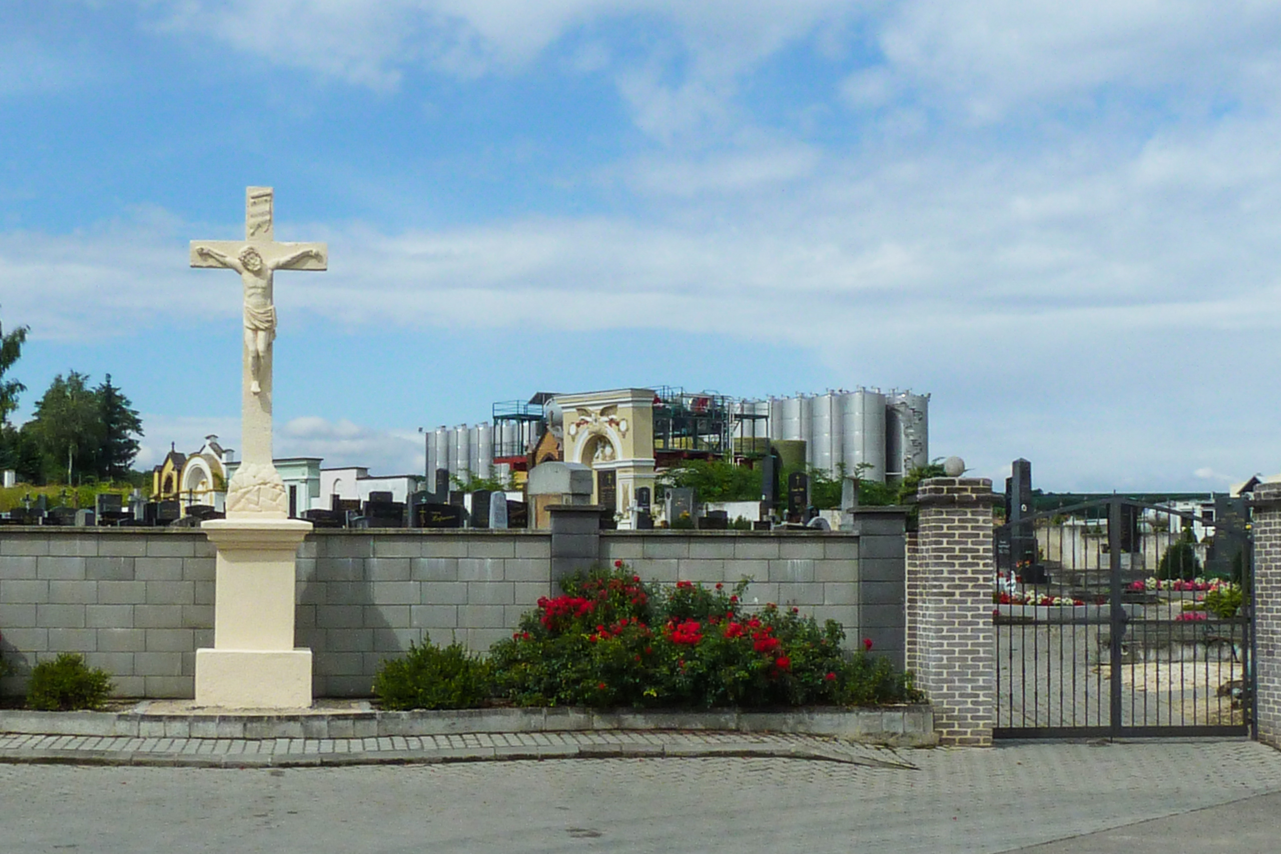 Friedhofskreuz vor den Stahltanks einer Kellerei